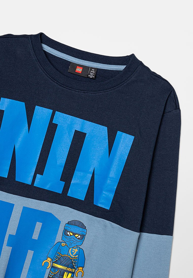Marineblaues und hellblaues Sweatshirt mit langen Ärmeln, das mit dem auffälligen Text "NINJA" und einer LEGO-Ninja-Grafik auf der Vorderseite versehen ist. Aus Baumwolle, mit Rundhalsausschnitt.