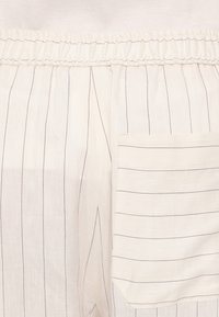 Lysfargede linbukser med vertikale stripes, med elastisk midje og en stor sidelomme. Glatt tekstur, avslappet passform.