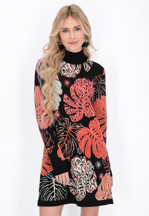 Black sweater dress with a turtleneck, featuring large floral patterns in red, green, and white. Long sleeves with ribbed cuffs.