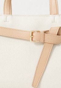 Borsa a mano in similpelle bianca con superficie testurizzata, dotata di una tracolla beige chiaro e una fibbia dorata per la chiusura.