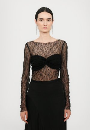 Must lille mustriga musta pitsiga pika varrukaga särk, millel on südamekujuline kaelus, koos ägeda musta seelikuga. Elegantne läbipaistev tekstuur.