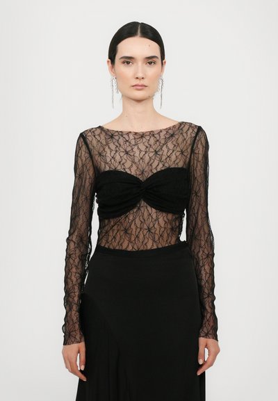 Zwarte kant lange mouwen top met bloemmotieven en een sweetheart halslijn, gecombineerd met een strakke zwarte rok. Elegante doorschijnende textuur.