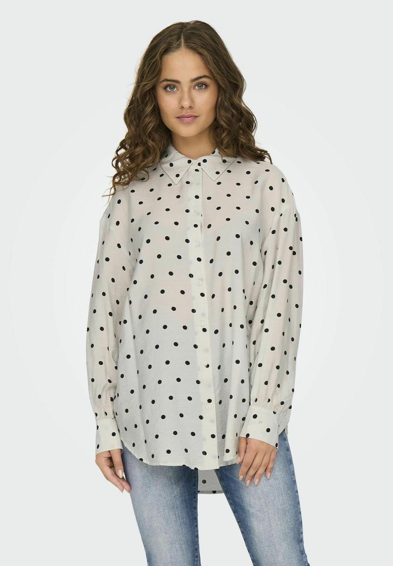 Licht, transparant button-up shirt met een kraag, met een witte achtergrond en zwarte stippen. Lange mouwen met knoopmanchetten.