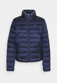 Doudoune matelassée bleu marine avec col montant, fermeture éclair sur toute la longueur, poches latérales et petit logo sur la poitrine.