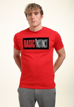 Rød bomulds t-shirt med et iøjnefaldende sort og hvidt "BASIC INSTINCT" grafik på forsiden. Korte ærmer og crew neck design.