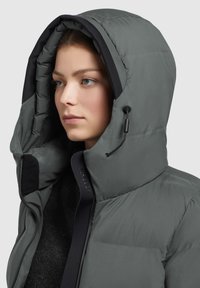 Giacca a vento grigia con un grande cappuccio. Presenta un'apertura con zip, un interno testurizzato e un cordino regolabile al cappuccio per una vestibilità ottimale.