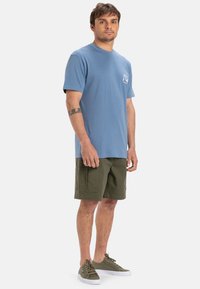 Blauwe katoenen T-shirt met een ronde hals en korte mouwen, gecombineerd met olijfgroene cargoshorts met meerdere zakken en een rechte pasvorm.