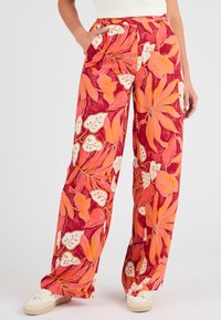 Pantaloni a palazzo rossi con motivo floreale e foglie tropicali in rosa, arancione e bianco. Presentano un elastico in vita e tasche laterali.