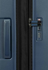 Hartsch suitcase in Dunkelblau mit einem Nylon-Reißverschluss, doppelten Schlössern und einem Kombinationsschloss neben dem Griff. Strukturiertes Oberflächendesign.