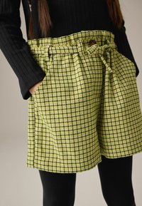 Grønne og gule ternede shorts lavet af tekstureret stof, med snøre i taljen, sidelommer og en afslappet pasform.