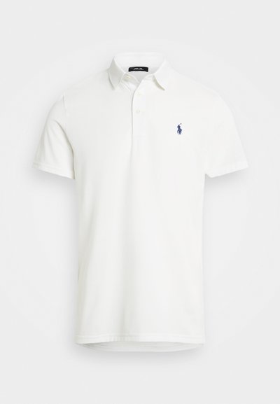 Camisa polo branca feita de algodão suave, com colarinho clássico, mangas curtas e um logótipo bordado em azul-marinho no lado esquerdo do peito.