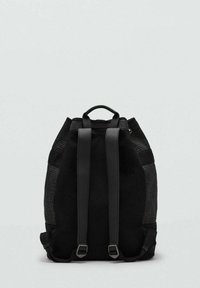 Mochila negra hecha de tela texturizada y cuero liso, con dos correas para los hombros y cierre en la parte superior con cordón.