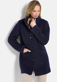 Marineblauer Wollmantel mit Reverskragen, vorderer Knopfverschluss und Seitentaschen. Bietet eine weiche Textur und eine lockere Passform.