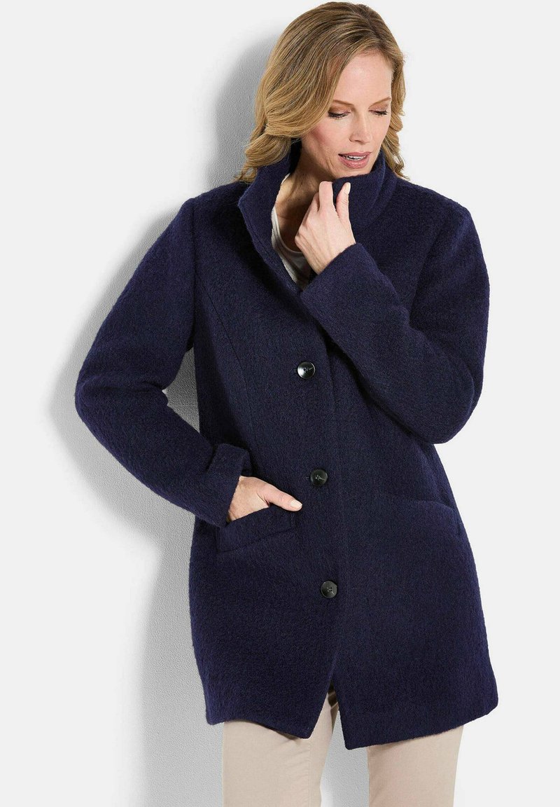 Marineblauer Wollmantel mit Reverskragen, vorderer Knopfverschluss und Seitentaschen. Bietet eine weiche Textur und eine lockere Passform.