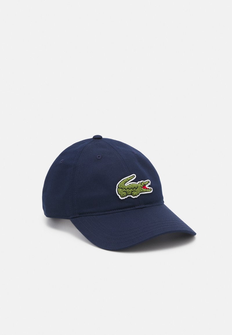 Gorra de béisbol de algodón en color azul marino con un logo de cocodrilo verde texturizado y acentos rojos, visera estructurada y correa ajustable en la parte posterior.