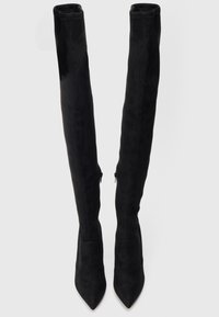 Melnas virsceļgala zābaki, kas izgatavoti no mīkstām zamšādām, ar smailu purngalu, slaidu siluetu un sānu rāvējslēdzējiem aizdarei.