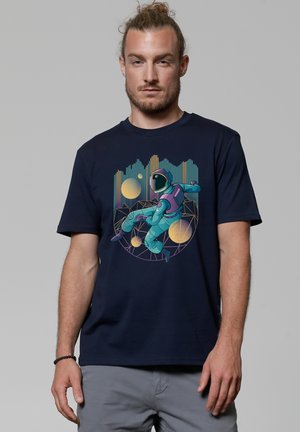 Navy blue t-shirt featuring a colorful astronaut graphic with geometric patterns and circular designs. Short sleeves and a crew neck.