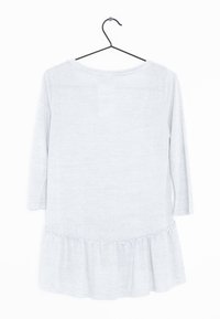 Haut gris clair à manches longues avec un col rond et un ourlet à volants. Fabriqué en tissu doux avec une texture lisse. Accroché à un crochet noir.