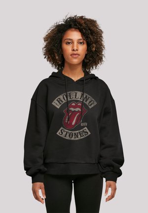 Black hoodie featuring a distressed Rolling Stones graphic with red tongue emblem. Loose-fit design with drawstrings and ribbed cuffs.