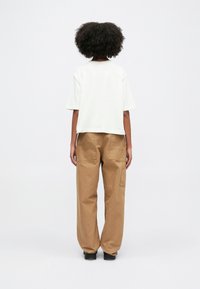 Kreem värvi lühikeste varrukatega T-särk, mis on sobitatud vaba lõikega khakivärvi cargo-pükstega, millel on küljekotid ja sirge jala disain.