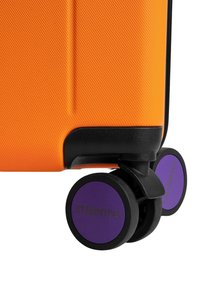 Orangener Koffer mit strukturierter Oberfläche, schwarzem Rand und lila Rädern mit Logo. Kompaktes Design mit vier multidirektionalen Rollen.