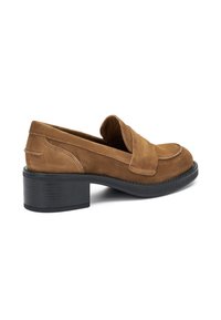 Mocassino in suede marrone con punta arrotondata, una fascia decorativa sul collo del piede e un tacco spesso nero. Texture liscia in tutto il prodotto.