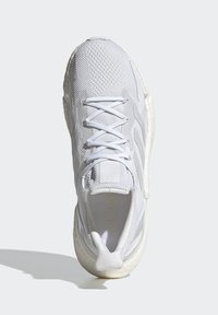 Baskets blanches avec une tige en mesh, des détails texturés et des lacets blancs plats. Présente un col rembourré et une semelle légère.