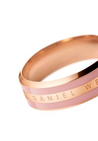 Rannekoru ruusukultaa, jossa on litteä muotoilu, vaaleanpunaiset emaliviivat ja kaiverrettu "DANIEL WELLINGTON" bändin varrella. Tasainen, kiiltävä pinta.
