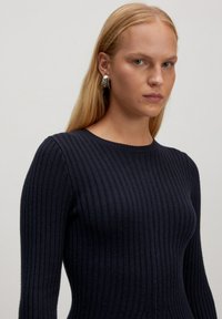 Marineblaue Rippstrickpullover mit Rundhalsausschnitt, figurbetonter Passform und langen Ärmeln. Verfügt über eine dezente Textur und eine glatte Oberfläche.
