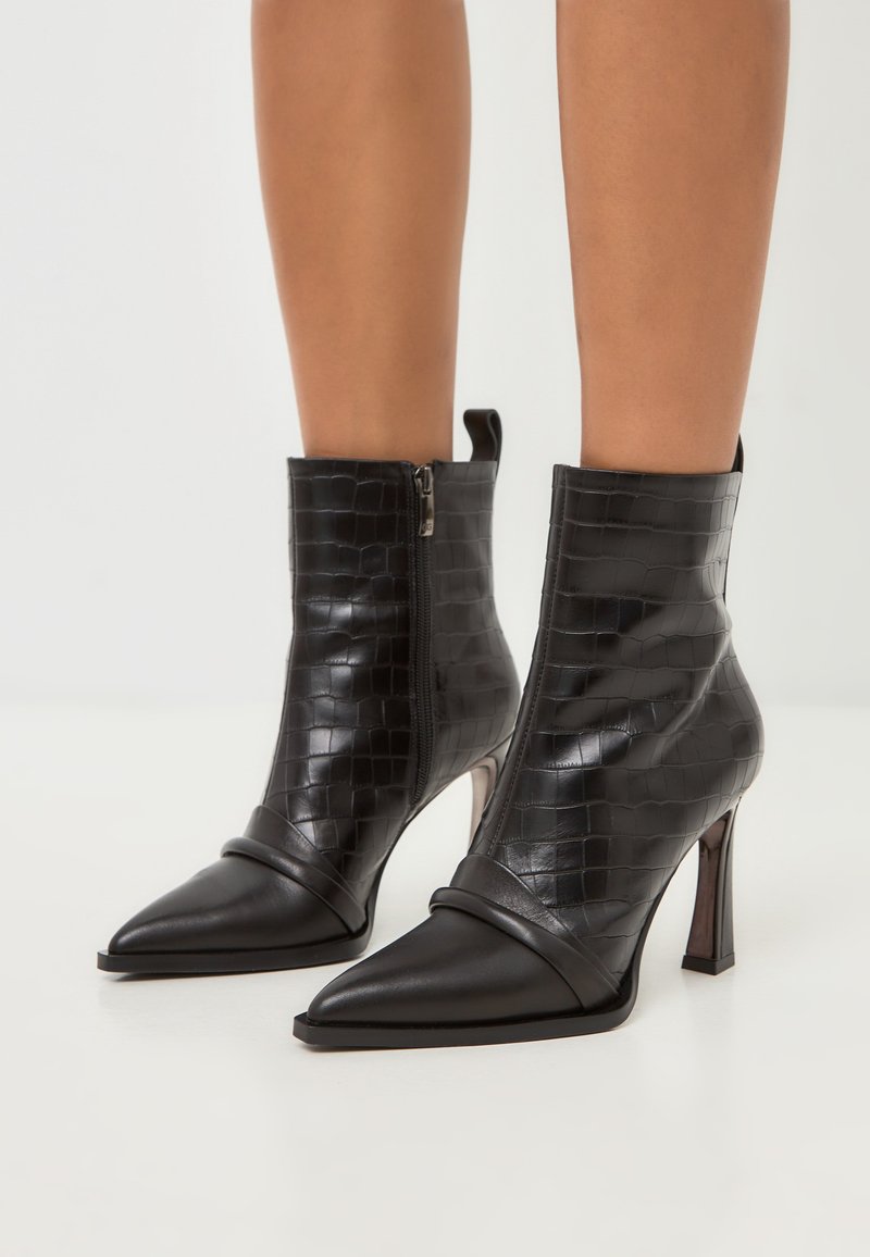 Stivali neri alla caviglia con motivo croc texturizzato, punta appuntita, tacco alto a stiletto e zip laterale per una facile indossabilità. Dettagli in pelle liscia.
