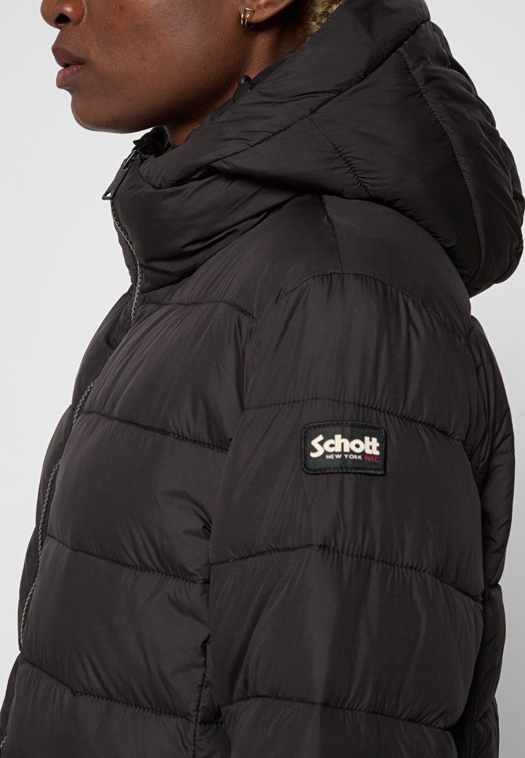 Veste rembourrée noire avec capuche, présentant une texture matelassée et une étiquette logo Schott sur la manche. Fermeture éclair à l'avant.