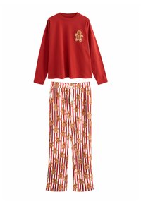 Röd långärmad skjorta med en pepparkaksfigur-applikation, kombinerad med vita byxor med ett pepparkaks-mönster på röda ränder.