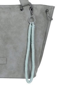 Borsa tote in finta suede grigia con texture liscia, hardware argento e un portachiavi di perline azzurro chiaro attaccato.