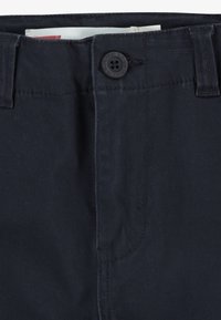 Pantaloni in cotone blu navy con chiusura frontale a bottone, passanti per cintura e una texture liscia con sottili dettagli di cucitura.
