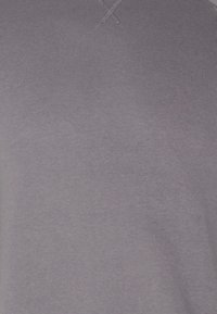 Paarse T-shirt met korte mouwen van zacht materiaal; beschikt over een eenvoudige ronde hals en subtiele stiksels nabij de halslijn.