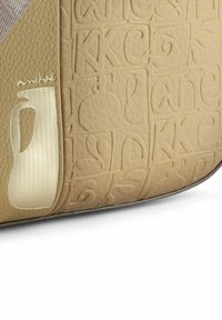 Beige Leder Tasche mit geprägten Mustern, einem glatten, reflektierenden Akzent und einem dezenten Logodetail. Strukturierte Oberfläche mit moderner Form.