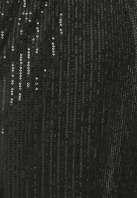 Tessuto nero con righe verticali di paillettes nere e argento sovrapposte, creando un motivo testurizzato e riflettente.