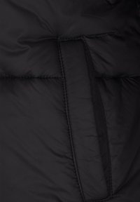 Czarna kurtka puchowa o pikowanym wzorze, z boczną kieszenią i przeszyciami zwiększającymi trwałość. Miękki, izolowany materiał.