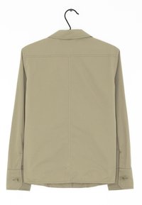 Langärmliges Hemd in hellem Khaki mit glatter Stofftextur, geknöpften Manschetten und Schalkragen. Hängt an einem Haken.