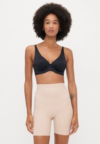 Μαύρο σουτιέν με ενίσχυση και scalloped άκρες, συνδυασμένο με απλά, ψηλόμεσα μπεζ σορτς. Λείος υφασμάτινος χαρακτήρας σε όλη την επιφάνεια.
