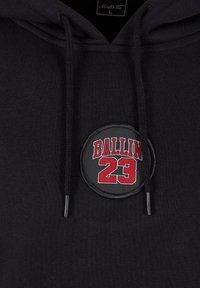 Sweatshirt negru cu glugă, realizat din bumbac, având un patch rotund cu "BALLIN' 23" în roșu pe un fundal negru, cu șnururi negre.