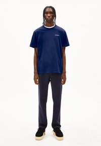 T-shirt en coton bleu marine avec un col rond, des manches courtes et un logo discret. Associé à un pantalon bleu marine et des chaussures à plateforme noires.