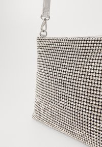 Zwarte handtas met rhinestones, verfraaid met zilverkleurige hardware; rechthoekige vorm, gladde textuur en een lange verstelbare schouderband.