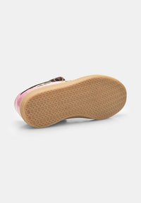 Base de chaussure rose et crème avec une semelle en caoutchouc texturée, ornée d'accents de motif léopard noir et d'une sangle Velcro sécurisée.