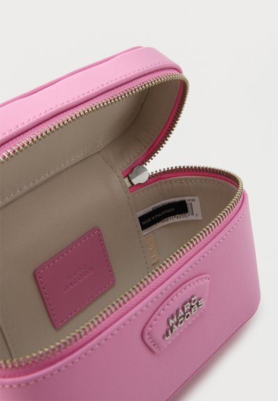 Ροζ καλλυντική τσάντα Marc Jacobs με μπεζ εσωτερικό, ασημένιο φερμουάρ μερικώς ανοιχτό αποκαλύπτοντας την ετικέτα της μάρκας και την ετικέτα στο εσωτερικό.