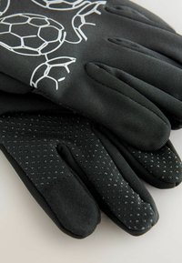 Schwarze Handschuhe mit einem gepunkteten Griffmuster, die oben ein weißes Schildkrötenmuster aufweisen. Hergestellt aus flexiblem Material für Komfort und Geschicklichkeit.