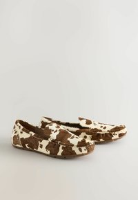 Koeienprint loafers van zacht materiaal met een bruin-wit patroon, voorzien van een instapontwerp en een platte rubberen zool.