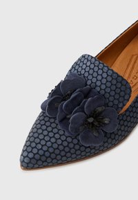Chaussure en velours bleu marine à bout pointu, motif à pois texturé et fleurs en tissu décoratives sur le dessus. Semelle en cuir visible à l'intérieur.
