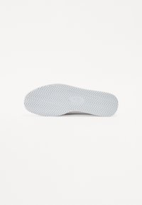 Fehér sneaker talp, halszálka mintázattal, sima felülettel és finom logónyomattal a saroknál.