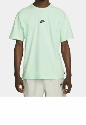 Hellmintgrünes, kurzärmeliges Baumwoll-T-Shirt mit einem schwarzen Nike-Logo auf der Brust, Rundhalsausschnitt und lockerem Schnitt.